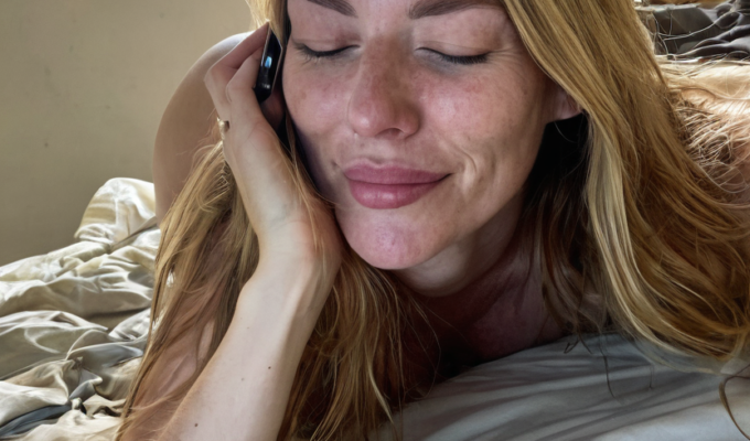 a woman lying on a bed holding a phone to her ear, smiling